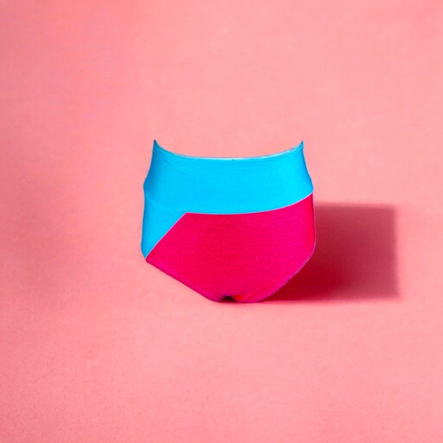 High waisted two tone briefs with a fun edgy cutout that can easily be paired with white, hues of orange, and peaches.